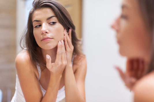 woman looking in the mirror touching her face looking for acne breakouts