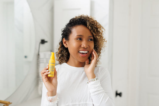 woman touching her face holding yellow bottle of Frownies Skin Serum