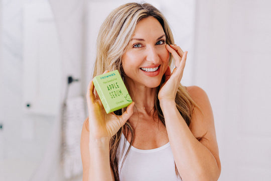woman holding a box of frownies apple serum applying serum to smooth crows feet