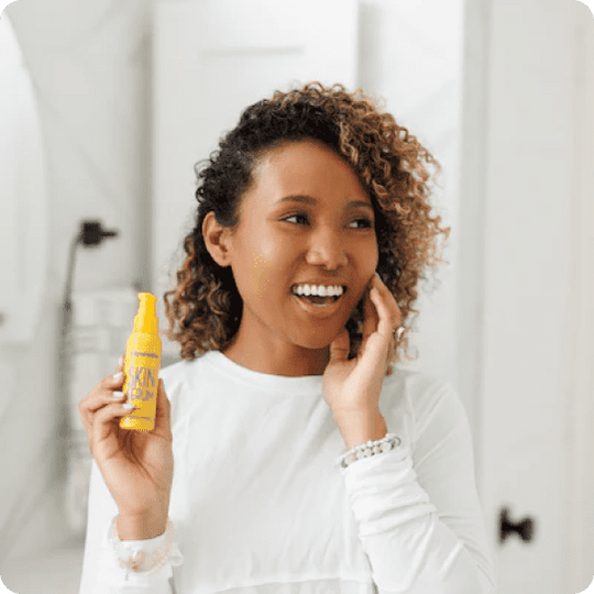 woman of color holding up a yellow bottle of frownies skin serum with vitamin c and e