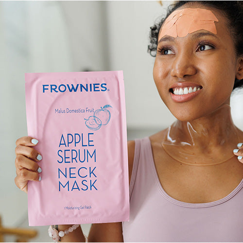 woman of color wearing frownies facial patches on forehead holding pink package and applying Neck Mask with Apple Stem Cell Serum Facial Patches, The Frownies   