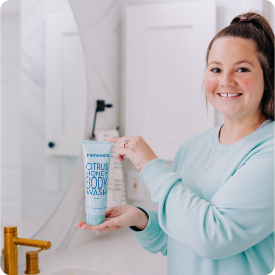 woman holding a blue bottle of frownies honey body wash
