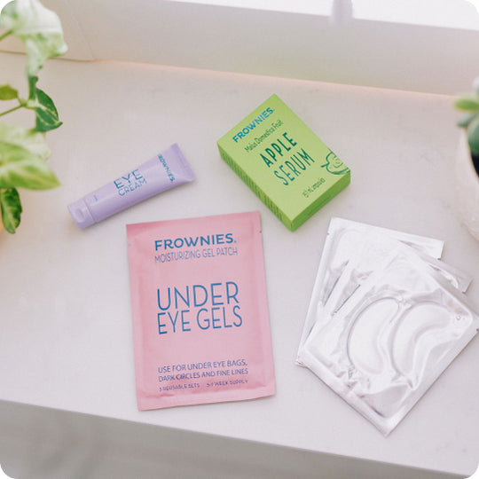 frownies natural skincare products including apple serum, eye cream, and under eye gels laid out on countertop