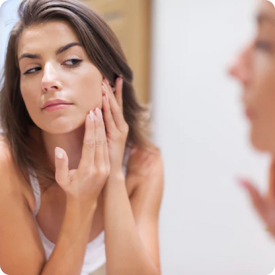woman looking at her skin in the mirror 
