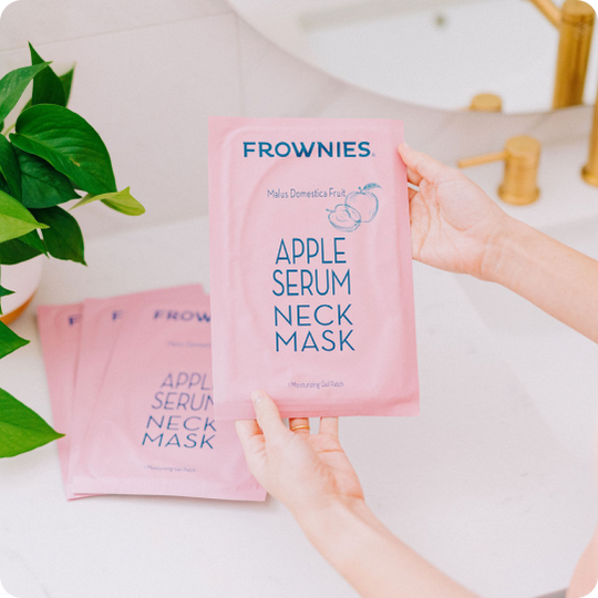 woman's hands holding pink package of apple serum neck mask for neck wrinkles and crepey skin