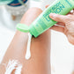 woman's leg with green tube of frownies Body Lotion with Essential Oils Skincare Products Frownies   