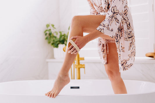 woman using body brush on her leg in the bathroom