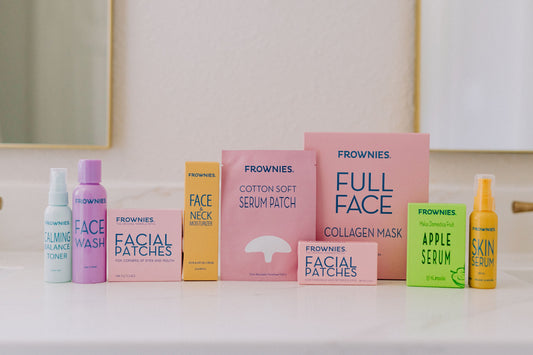 A bathroom counter with the full collection of Frownies Facial Patches and skincare products in their brightly colored packaging