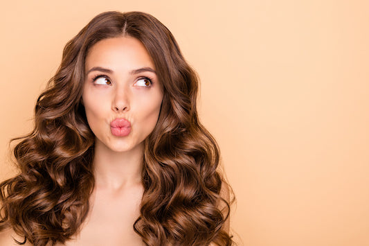woman with long brown wavy hair pursing lips like giving a kiss