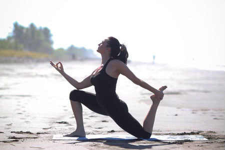 woman performing yoga pose on beach