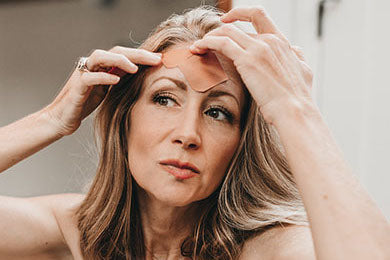 woman applying paper Frownies Facial Patches to forehead wrinkles
