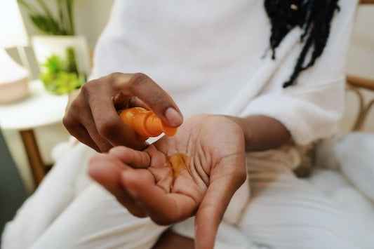african american woman pouring skin serum oil into her hands