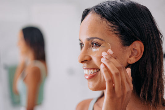 Woman with an under eye gel applied to her under eye smiling in a brightly lit room
