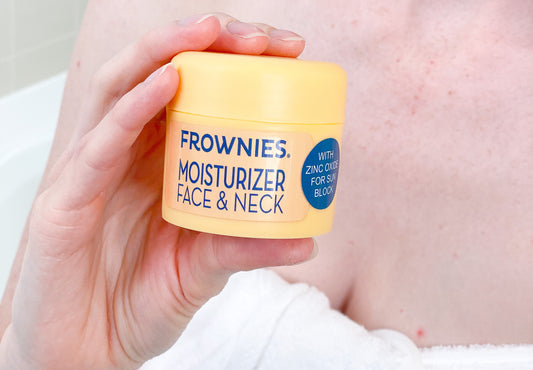 bust of a woman in a towel holding a container of Frownies Moisturizer with Zinc Oxide