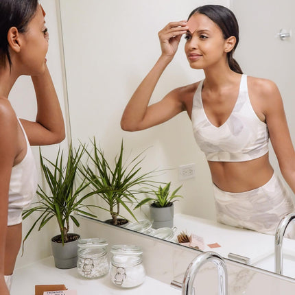 woman looking in mirror applying frownies to forehead
