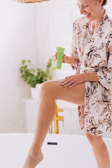 woman applying body lotion with essential oils to upper thigh