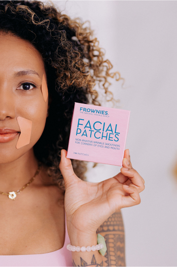 half of woman's face holding up a pink box of frownies facial patches for corners of eyes and mouth