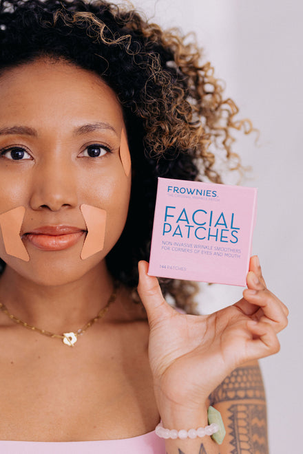half of woman's face holding up a pink box of frownies facial patches for corners of eyes and mouth