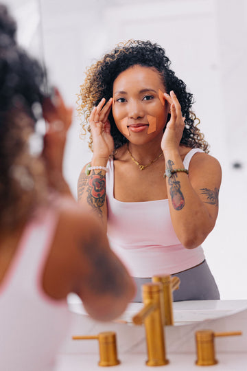 woman of color applying frownies facial patches in mirror to the corners of the eyes and mouth
