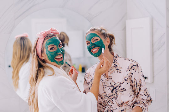 Two women with skin care products applying blue green algae clay mask