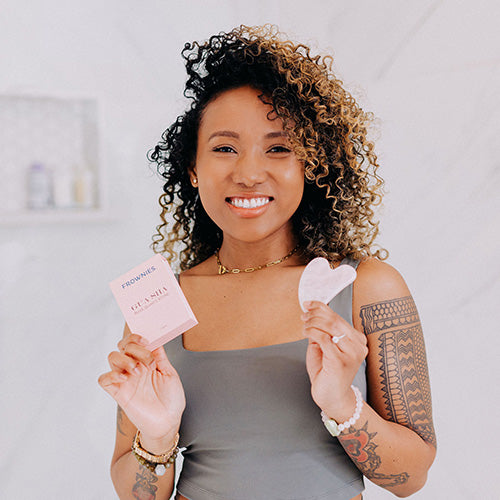 woman of color with curly hair holding pink box and rose quartz gua sha stone