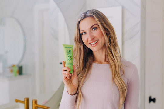 woman holding green bottle of body lotion with essential oils