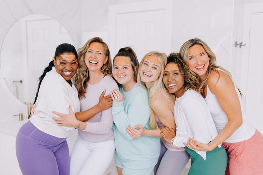 six smiling women holding pink boxes of frownies wrinkle patches wearing frownies facial patches on forehead to smooth 11 lines