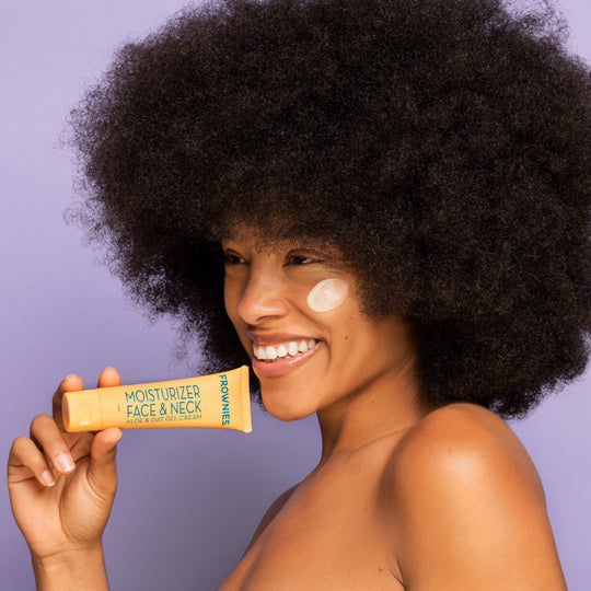 woman of color with natural hair holding frownies aloe and oat gel moisturizer for dry skin