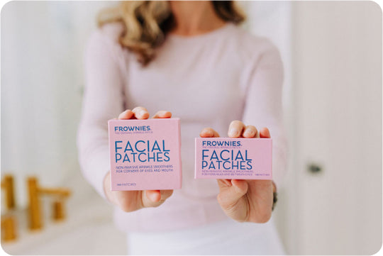 woman's hands holding out two pink boxes of frownies facial patches