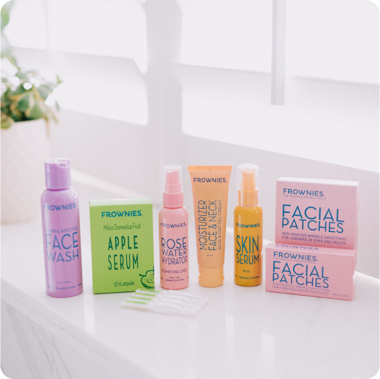 seven frownies natural skincare products including pink boxes of wrinkle patches and serums lined up on a bathroom counter