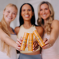 Three women holding Frownies Face & Neck Moisturizer bottles