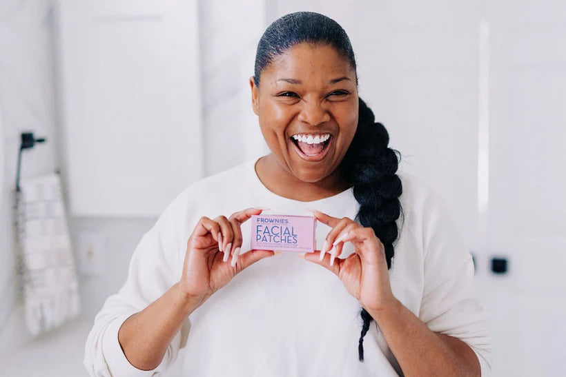 smiling woman with long, dark hair in braid holding box of frownies facial patches for forehead and between the eyes