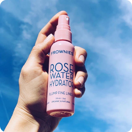 hands holding rose water facial toner with hyaluronic acid against blue sky