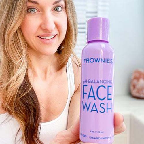Woman holding a purple bottle of Frownies pH Balancing Face Wash 