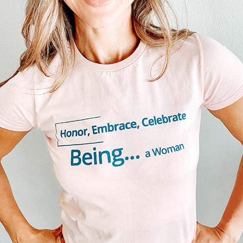 pink tee with blue text that reads Honor, Embrace, Celebrate, Being...a Woman