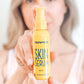 Woman holding a 59 mL pump orange bottle of the Frownies Skin serum