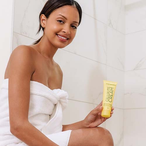 Smiling young woman holding cellulite cream by Frownies