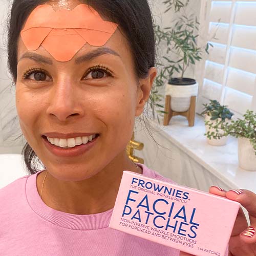 Woman with Frownies Wrinkle Patches on her forehead wrinkles and elevens between the eyes holding a pink box of Frownies