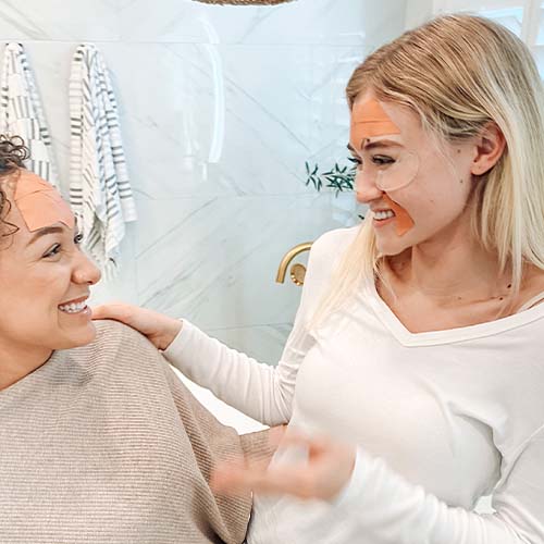 Two women with Frownies wrinkle patches on their faces and Frownies Eye Gels on the under eye area.